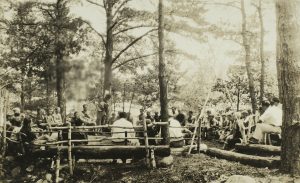 campers and staff sitting around campfire early 20th century